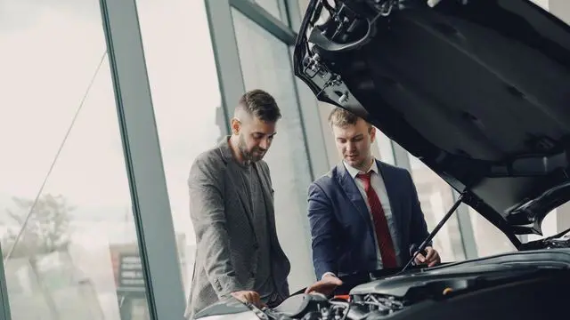 Man discussing buying a new car with salesman at dealership Man discussing buying a new car with salesman at dealership